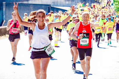 Two runners at the finish line smile and wave their hands